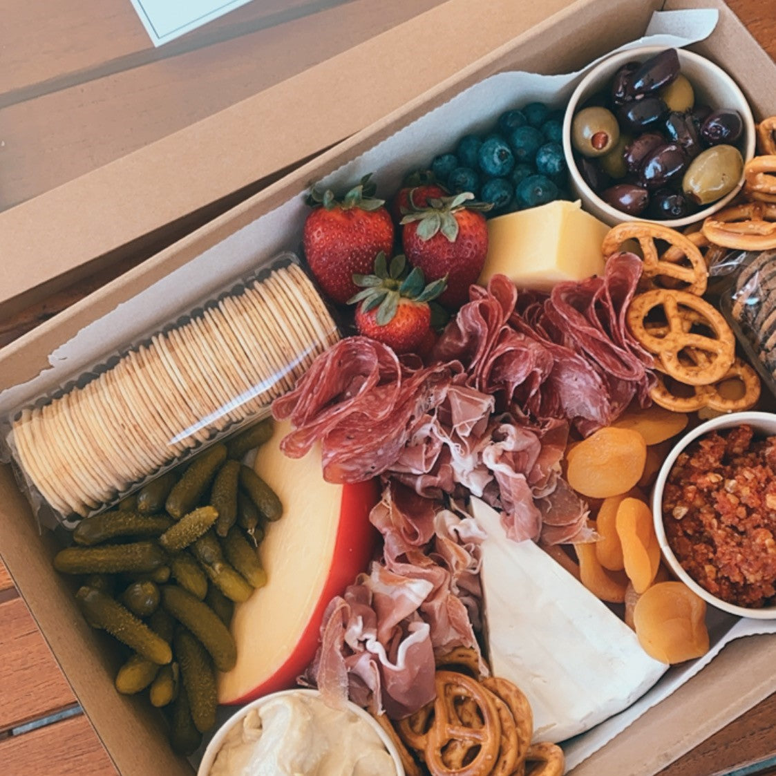 Serves up to 8 people.  Medium Grazing Boxes are an intelligent way to conveniently cater any casual or formal event or occasion and contains:  Cheese - two hard, one soft Cured meat (200g two varieties - upgrade includes additional 150g) Dip - two variations Antipasti items, dried and fresh fruit (assorted) Including a substantial range of high-quality, locally sourced produce consisting of premium cheese, cold meats, nuts and gluten (unless specified).