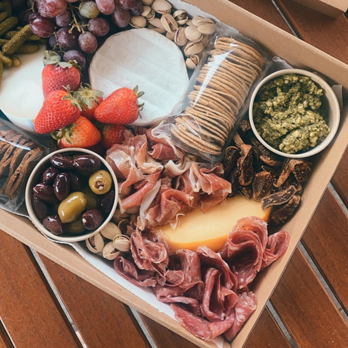 Serves up to 8 people.  Medium Grazing Boxes are an intelligent way to conveniently cater any casual or formal event or occasion and contains:  Cheese - two hard, one soft Cured meat (200g two varieties - upgrade includes additional 150g) Dip - two variations Antipasti items, dried and fresh fruit (assorted) Including a substantial range of high-quality, locally sourced produce consisting of premium cheese, cold meats, nuts and gluten (unless specified).