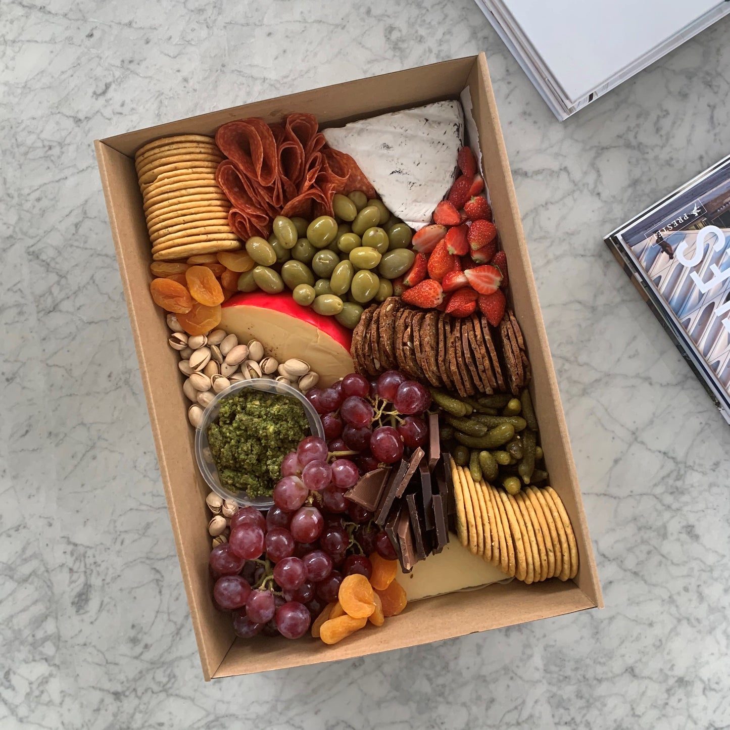 Serves up to 8 people.  Medium Grazing Boxes are an intelligent way to conveniently cater any casual or formal event or occasion and contains:  Cheese - two hard, one soft Cured meat (200g two varieties - upgrade includes additional 150g) Dip - two variations Antipasti items, dried and fresh fruit (assorted) Including a substantial range of high-quality, locally sourced produce consisting of premium cheese, cold meats, nuts and gluten (unless specified).